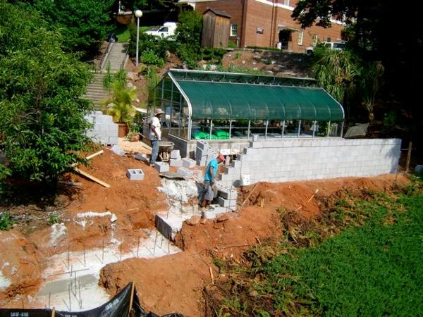 August 2008: After foundation is poured and reinforced with rebar, workers begin constructing cement block wall to enclose the rear of the greenhouse and end at the pedestrian footbridge.